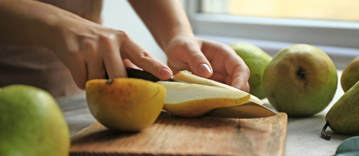 Woman cutting ripe pears on table