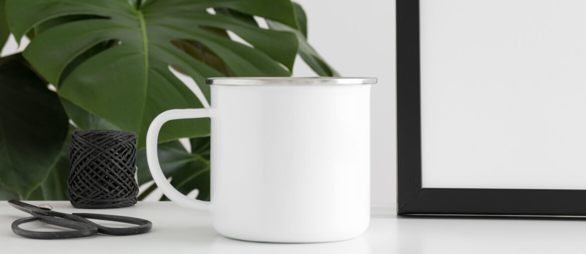 Enamel mug mockup with workspace accessories and a monstera plant.